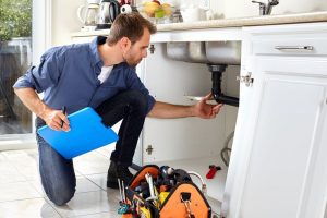 Plumber repairing drain pipe under a sink